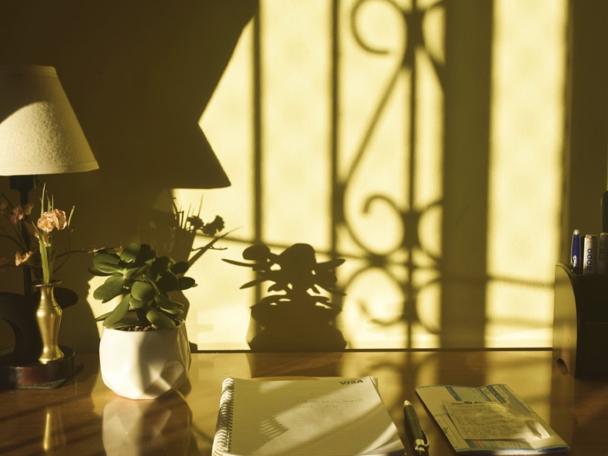 A single desk lamp lit at night, warm bulb, everything else dim.