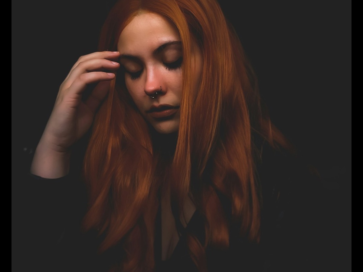 A woman in her forties in a black turtleneck, half-lit, on a rooftop terrace.